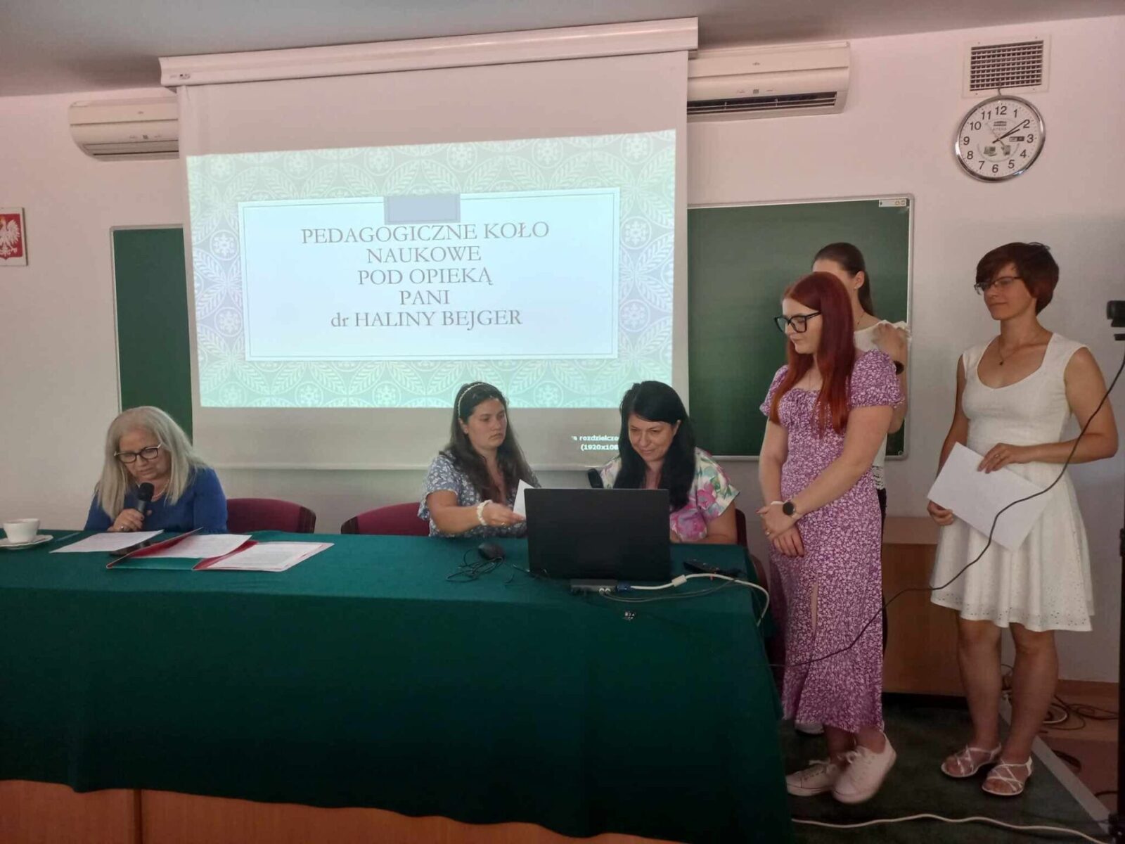 Studenci przy stoliku prowadzą prezentację podczas konferencji naukowej "Zjednoczeni nauką"
