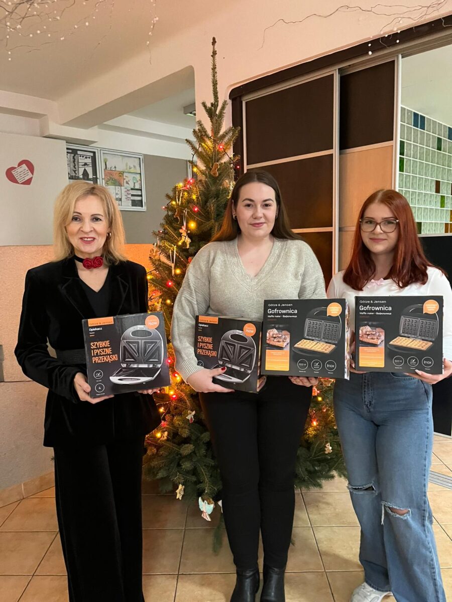 Dwie studentki z Dyrektorką Chełmskiego Centrum Pomocy Dziecku i Rodzinie podczas przekazania darów od studentów. W rękach trzymają opiekacze do kanapek i gofrownice.